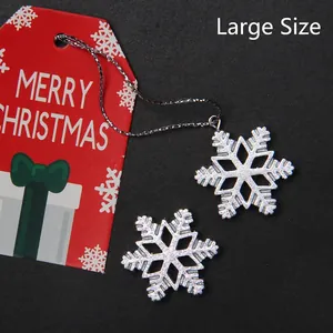 Detailed close-up of large silver glitter snowflake charms and Merry Christmas tag