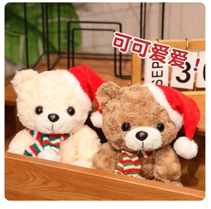 Close-up of small beige and brown Christmas teddy bears with red hats and striped scarves