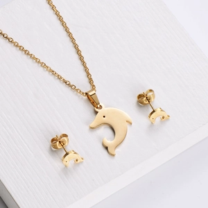 Golden dolphin jewelry set with necklace and stud earrings on a textured background