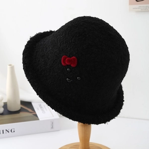 Detail of plush black cloche hat with a red velvet bow and bead on a wooden stand
