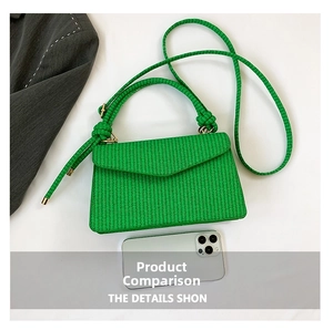 Detailed view of green woven envelope crossbody bag showing texture and size with a phone