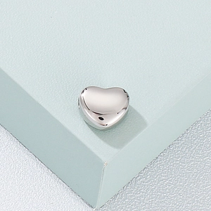 Macro shot of a polished silver heart-shaped metal bead with a smooth reflective surface