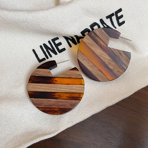 Detailed macro view of geometric wooden earrings with amber resin on linen fabric
