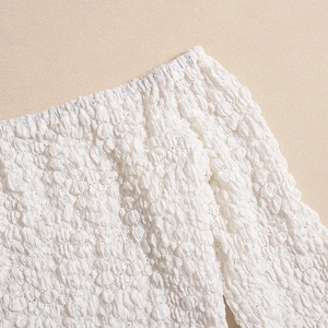 Detail of white 3D bubble textured fabric with elastic gathered hem on a dress