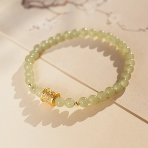 Detail of jade bead bracelet with a gold luck charm and Chinese character Fu engraving