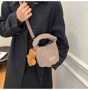 Close-up of plush lamb wool bucket bag with cute bear charm and woven shoulder strap