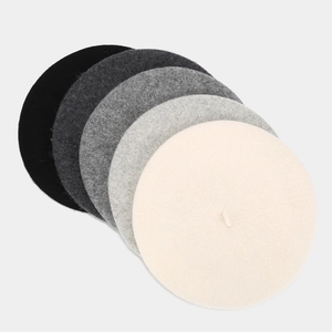 Detail of wool beret hats in gray and cream colors showing thick felt material texture