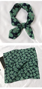 Détail d'un foulard en coton et lin vert avec un élégant motif de trèfle floral
