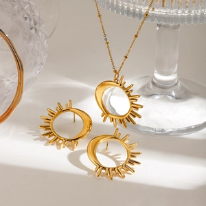 Detail of 18K gold-plated necklace and earrings set featuring sun and moon celestial motifs