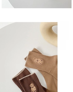 Détail de chaussettes mi-mollet aux tons terre avec côtes et broderie d'ours en peluche