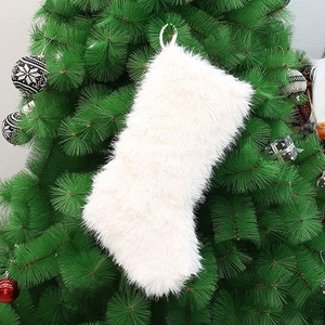 White faux fur Christmas stocking hanging on a decorated tree with festive ornaments