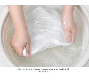 Close-up of hand-washing a transparent, reusable clothes dust cover in a basin