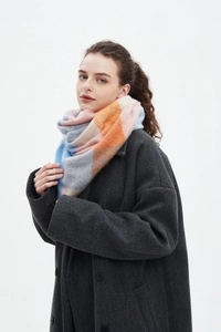 Detail of colorful plaid triangle scarf with soft yarn texture worn on a winter coat