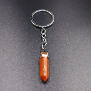 Detail of a hexagonal orange sandstone crystal pendant on a silver metal keychain ring
