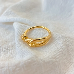 Primo piano di un anello minimalista in acciaio inossidabile dorato con nodo