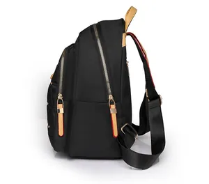Vista lateral de la mochila de tela oxford negra con cremalleras doradas y asa camel