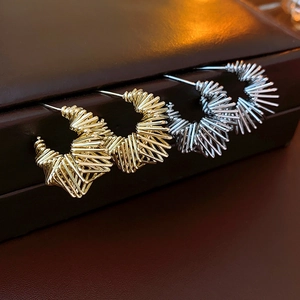 Detail of twisted C-shaped earrings in gold and silver finish on a dark jewelry box