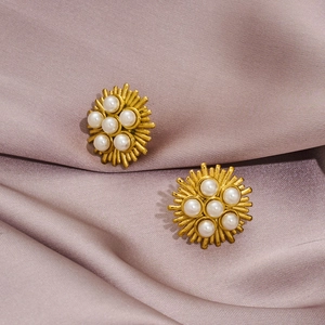 Close-up of vintage gold sunburst earrings with white pearls on purple silk fabric