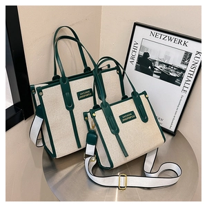 Detail of canvas tote bag set with green leather trim and wide striped shoulder strap