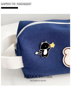 Detail of cute cat enamel pin with yellow star on a blue canvas bag with white strap