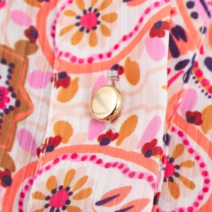 Macro shot of paisley floral print fabric and gold dome metal button on shirt dress