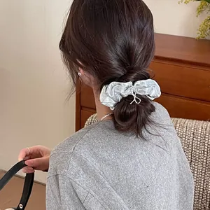 Silver metallic scrunchie styled on a brunette bun hairstyle with reflective finish
