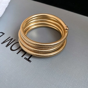 Detailed close-up of golden Tubogas coiled bracelet showing flexible ribbed metal texture