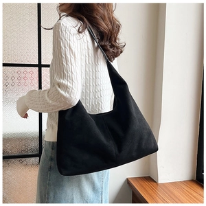Detailed view of black matte oversized tote bag on shoulder with soft natural indoor lighting