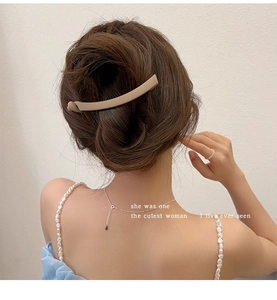 Macro detail of a matte beige banana hair clip styled on an elegant low ponytail