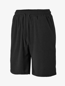 Detail of black men's casual shorts showing waffle textured fabric and drawstring waist