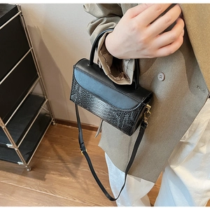 Detail of black faux crocodile texture and gold hardware on retro crossbody bag
