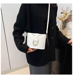 Detailed view of a white bucket bag with a gold D-ring buckle and a slim strap