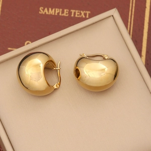 Macro shot of chunky gold geometric hoop earrings on a beige velvet jewelry display
