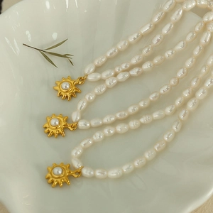 French freshwater pearl necklace with gold sunflower pendant on a shell tray