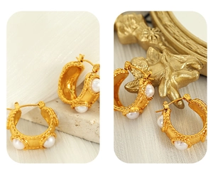 Macro detail of 18k gold C-shaped earrings featuring inlaid pearls on vintage velvet