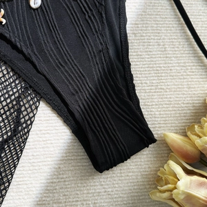 Detailed view of black ribbed fabric with natural white seashell trim and bohemian styling