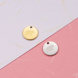 Detailed view of 18K gold and silver stainless steel bear pendants on a textured background