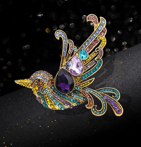 Close-up of bird brooch featuring colorful crystals and a large purple teardrop gem