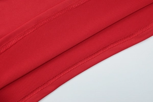 Close-up of red fabric texture with professional double-stitched hem on a slim-fit dress