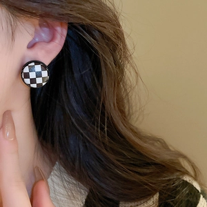 Minimalist geometric round checkerboard earrings with black and white leather finish on model
