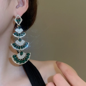 Macro shot of vintage emerald-green drop earrings with layered diamond tassels