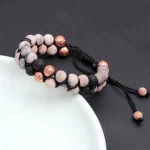 Dettaglio di perle in diaspro zebra rosa e pietra lavica su bracciale intrecciato
