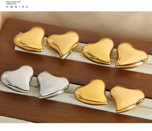 Macro detail of glossy heart-shaped stud earrings in gold and silver on jewelry stand