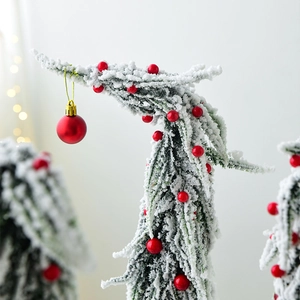Miniature snow-flocked Christmas tree with red berry ornaments and festive warm lighting