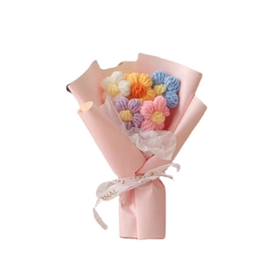 Hand-knitted colorful wool flower bouquet wrapped in pink paper with a white ribbon