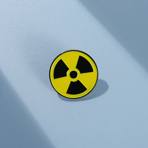 Macro detail of round radioactive symbol enamel pin with black clover on yellow background