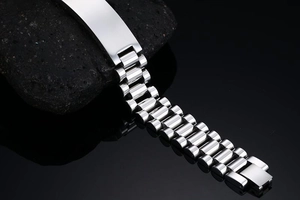 Macro shot of silver stainless steel curved ID plate bracelet on a black rock surface