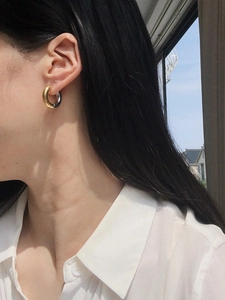 Close-up of chunky mixed-metal hoop earring in gold and silver finish on ear