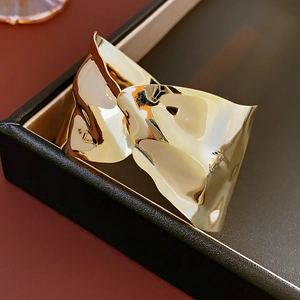 Bracciale rigido dorato ondulato lucido presentato in una scatola regalo di lusso