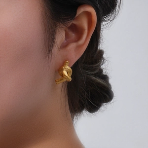 Close-up of stylish gold knotted earrings showing a minimalist metallic brushed finish